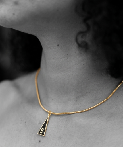 Medalla Inicial "E" de la Serie Triangular en latón con chapado en oro de 18K y esmalte negro.